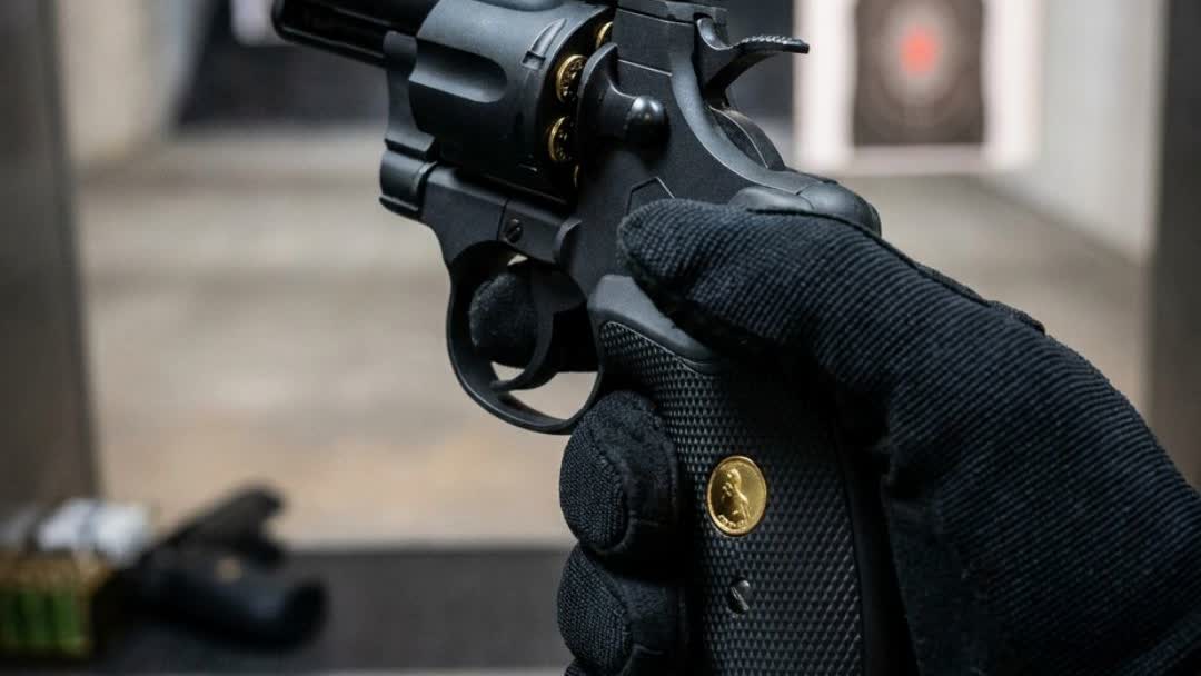 Gloved hand holding the snub-nose CO2 airsoft revolver at an indoor range
