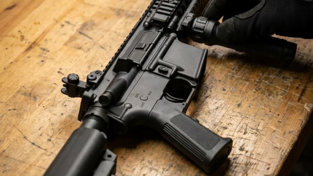 Close-up of the MK18 AEG quad-rail handguard with a gloved hand fitting an accessory